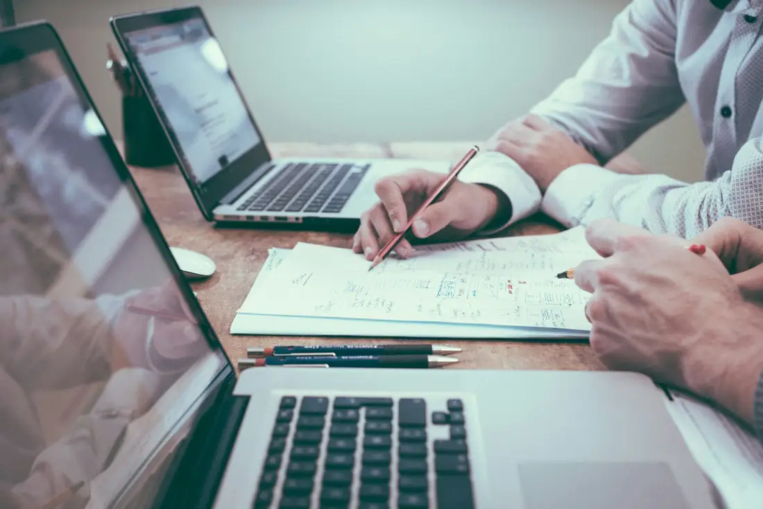 Consultor e cliente analisando números e anotações ao lado de um notebook