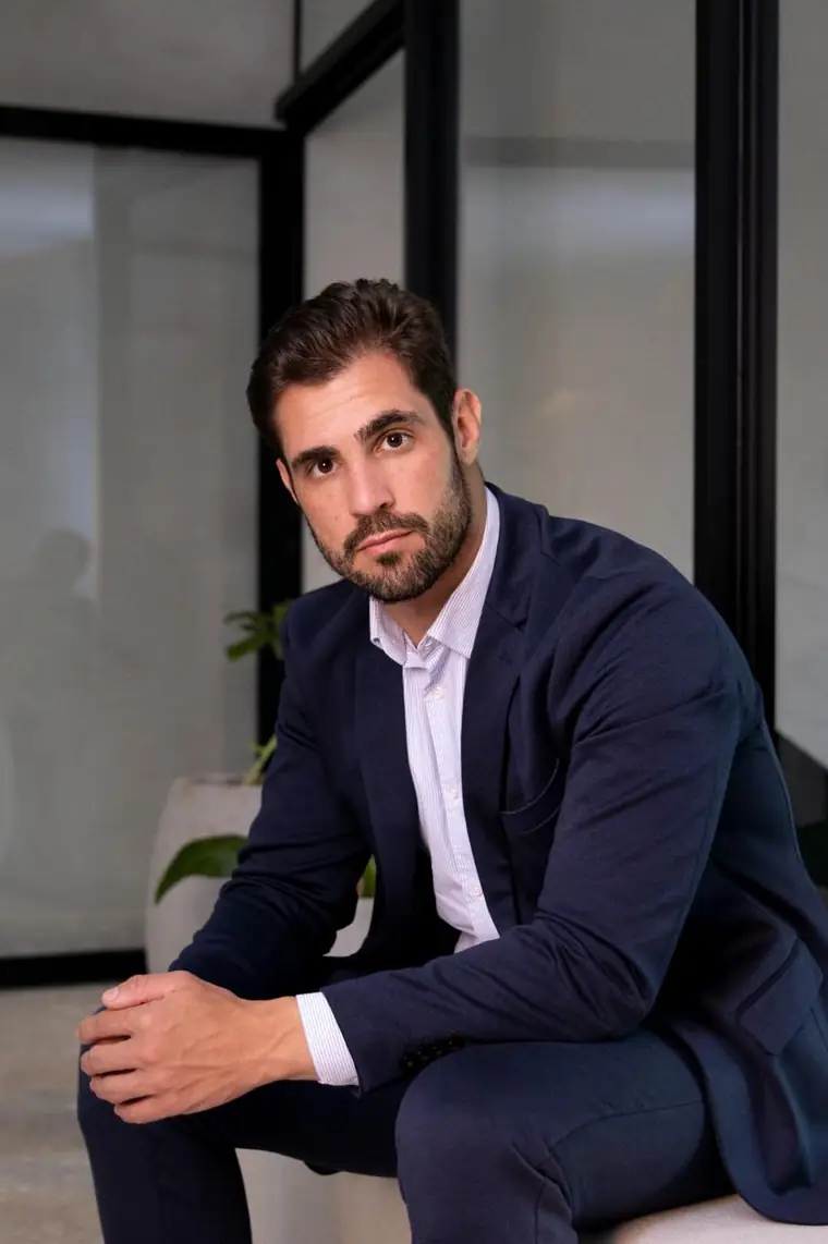 Rafael Moreno sentado, de terno azul-marinho, em seu escritório