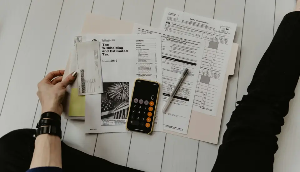 Mãos organizando contas e boletos ao lado de uma calculadora